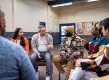 A group of people sit in a circle and talk.