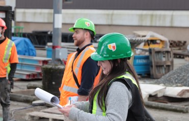 A woman in a hard-hat at an outdoor worksite.