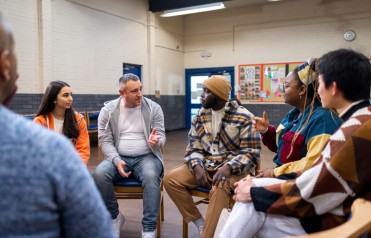 A group of people sit in a circle and talk.