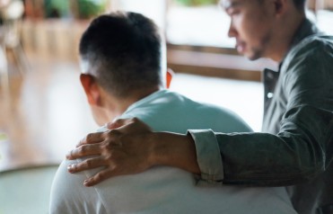 A man puts his hand on a person's shoulder.