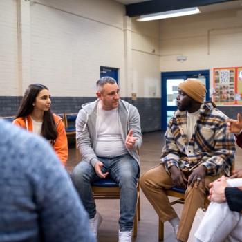 A group of people sit in a circle and talk.