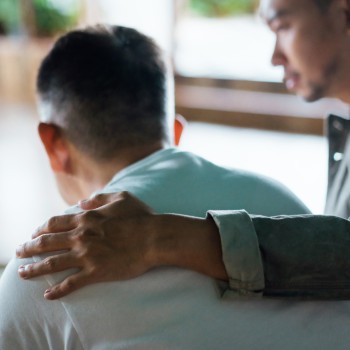 A man puts his hand on a person's shoulder.