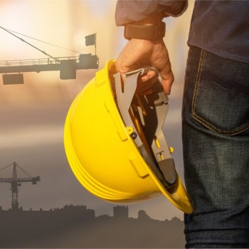 A person's hand holding a hard hat.