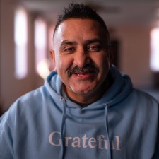Mike, a South Asian Canadian man, smiling. He is wearing a sweatshirt that says "grateful."