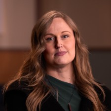 Jenny, a woman with long wavy light brown hair and subtle make-up, smiles at us. 