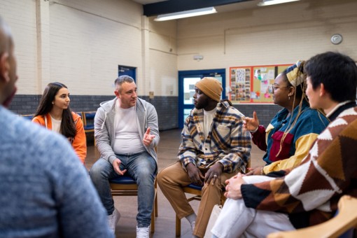 A group of people sit in a circle and talk. 