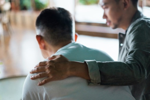 A man puts his hand on a person's shoulder.