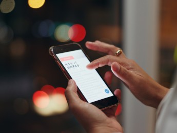 Someone scrolls through a webpage titled "How It Works" on a phone screen.