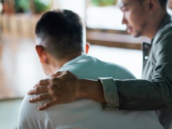 A man puts his hand on a person's shoulder.