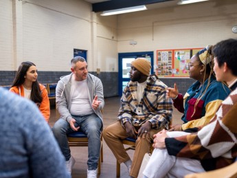 A group of people sit in a circle and talk. 