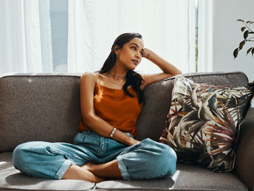 Woman sitting cross-legged on couch, looking off to the right